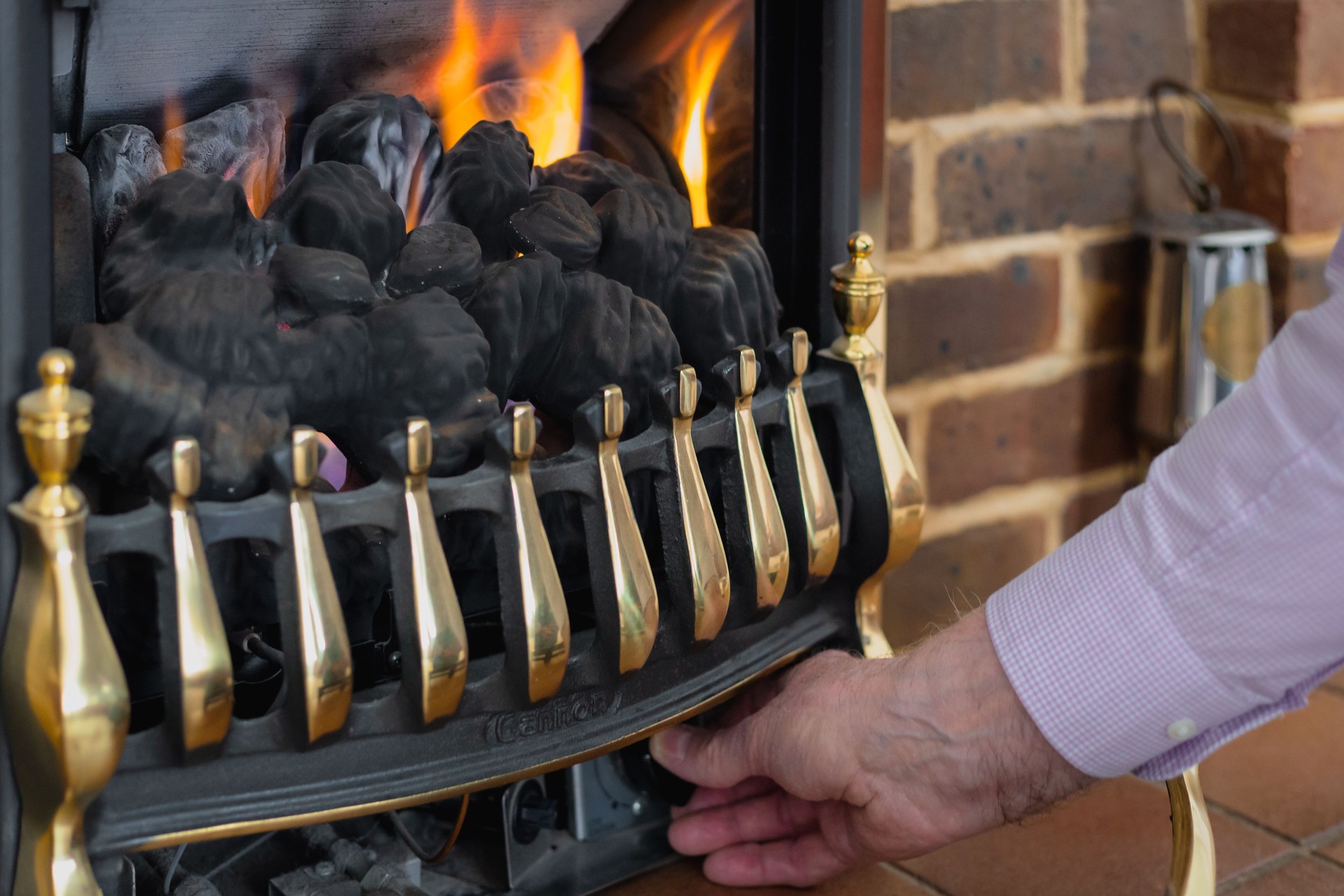 Senior man adjusting heat on gas fire at home