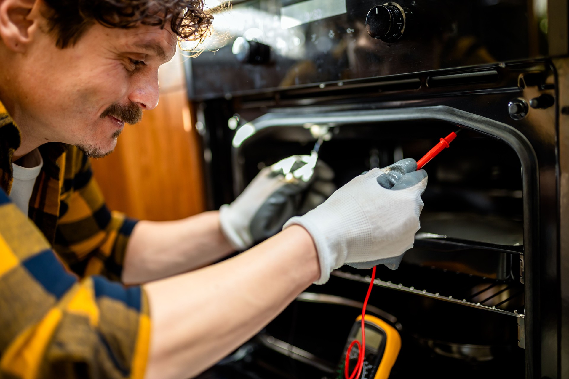 Latino man using multimeter for fixing stove.