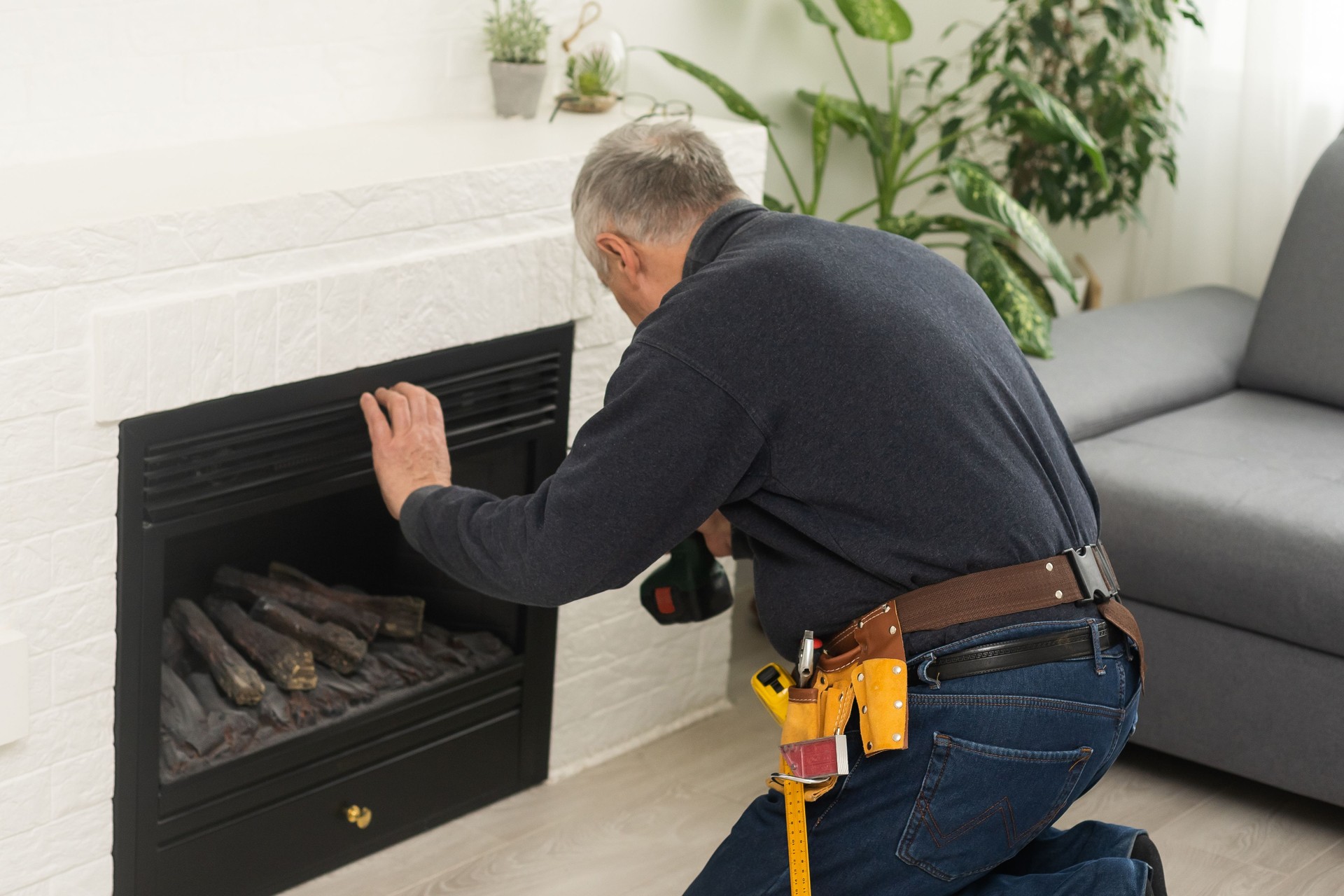 an elderly man repairs a fireplace